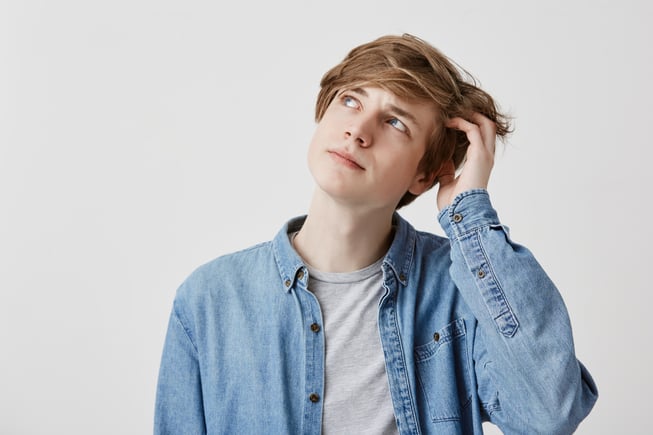 stunned-fair-haired-man-with-blue-eyes-looks-with-puzzled-expression-up-tries-remember-something-important-pensive-dreamy-young-man-poses-indoors